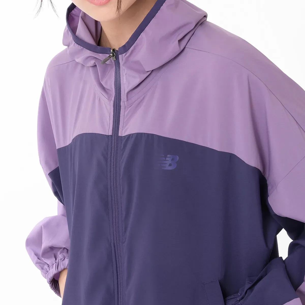 Jaqueta feminina New Balance roxa com capuz e zíper frontal, vista detalhada.